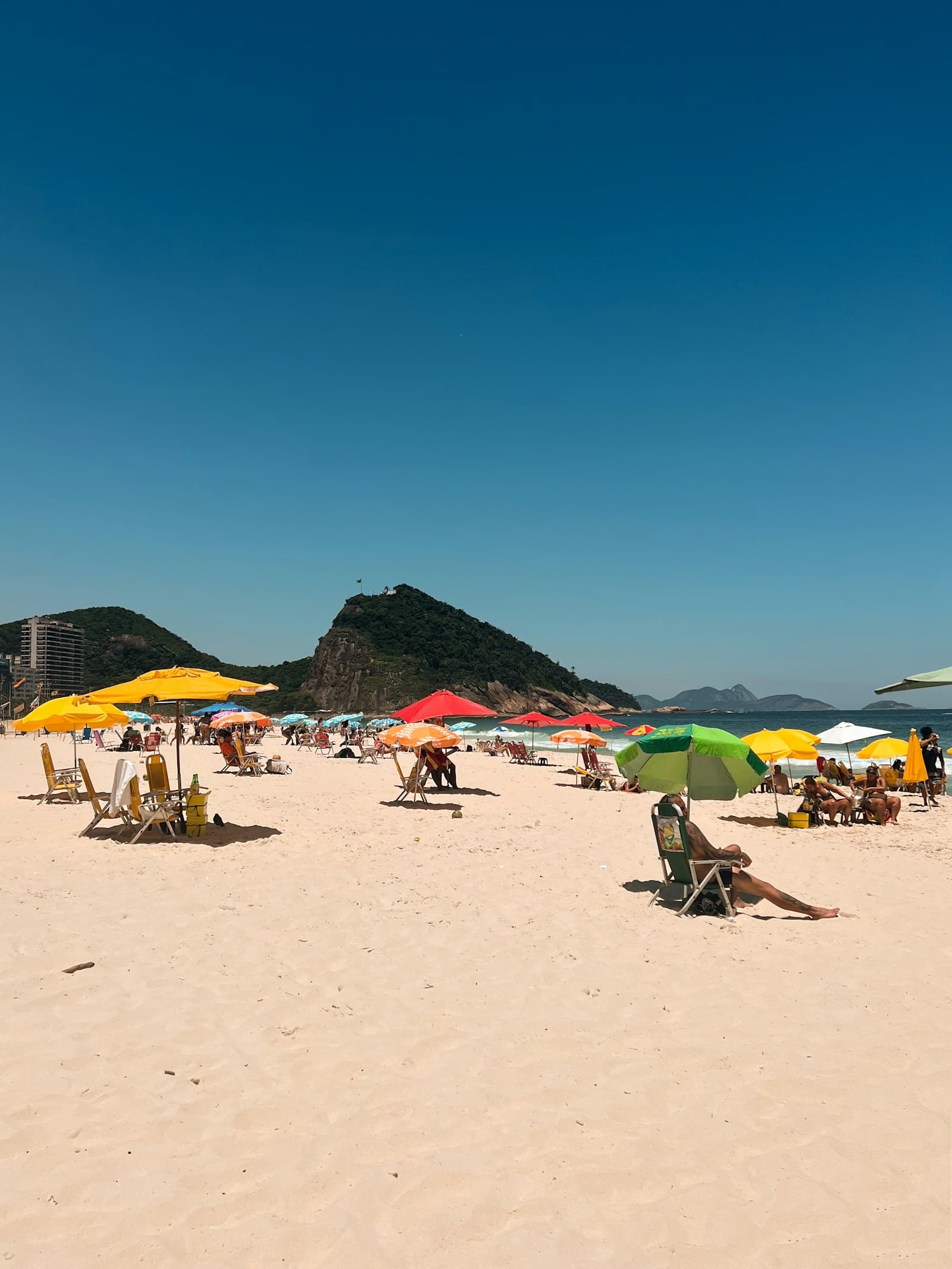 Families relaxing beneath umbrellas on Copacabana Beach in Rio de Janeiro