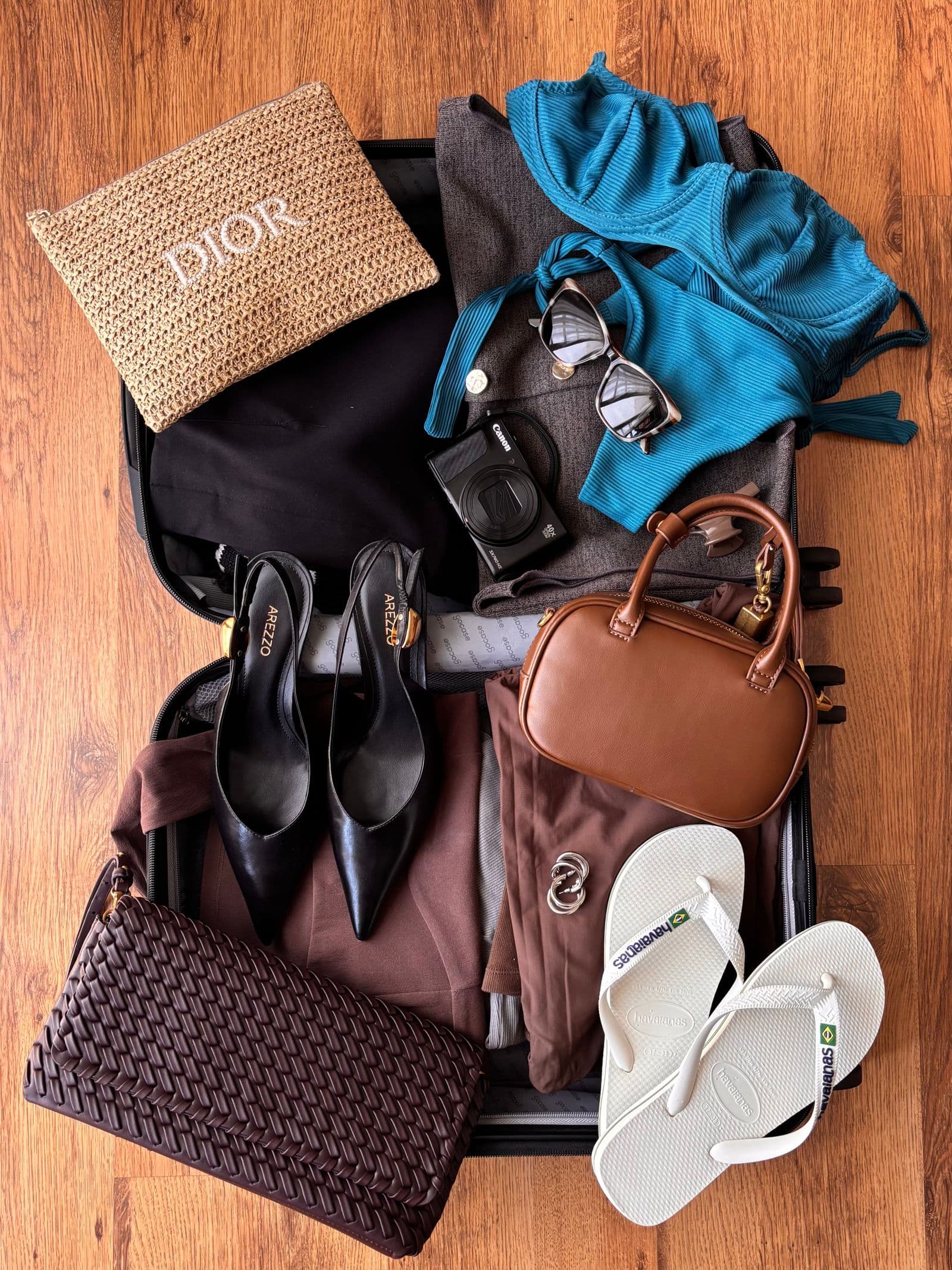 Summer travel essentials arranged inside an open suitcase