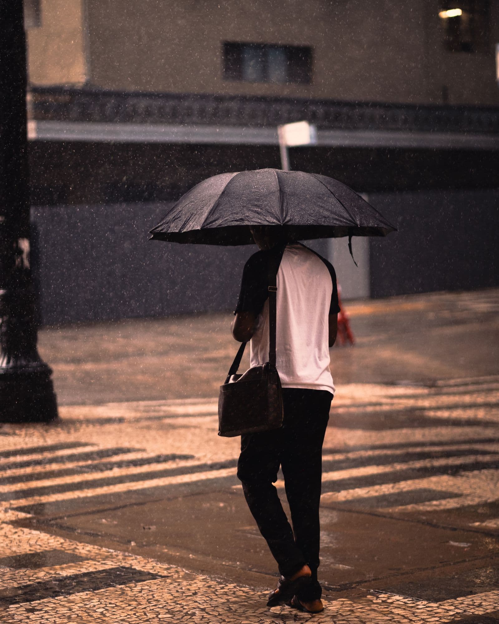 A pedestrian carrying an umbrella on a rainy street in Sao Paulo